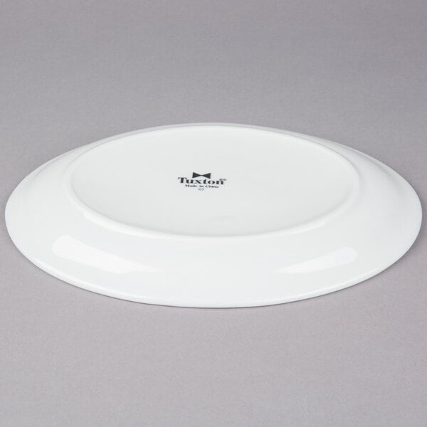 A white Tuxton oval china platter with a black rim.