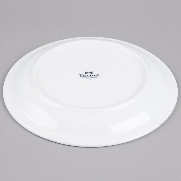 A Tuxton Colorado white china plate with a small logo on the rim.