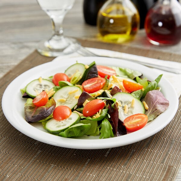 A Tuxton Colorado white narrow rim china plate with a salad of tomatoes and cucumbers.