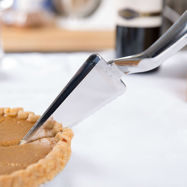 A silver plastic pie server being used to cut a slice of pie.