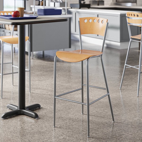 A Lancaster Table & Seating natural finish cafe bar stool at a table in a kitchen.