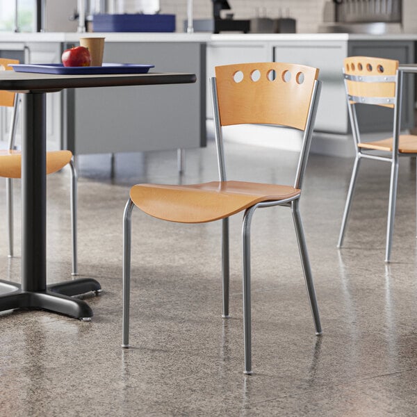 A Lancaster Table & Seating natural finish cafe chair next to a table.