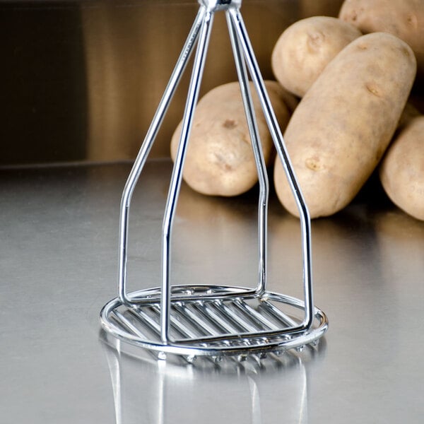 A Thunder Group potato masher on a counter with potatoes in a metal basket.