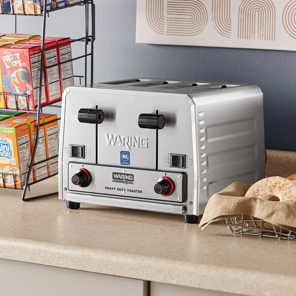 A Waring commercial toaster on a counter next to bread.