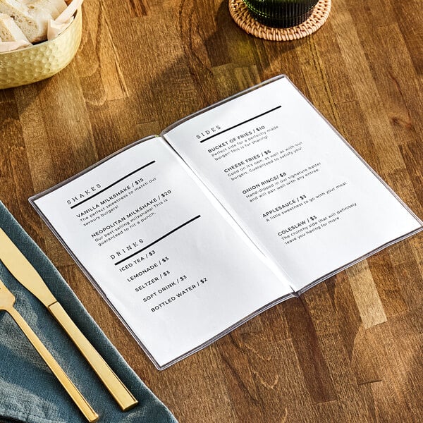 A H. Risch clear menu cover on a table with a knife and fork.