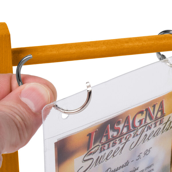A hand holding a Menu Solutions oak wood table tent.