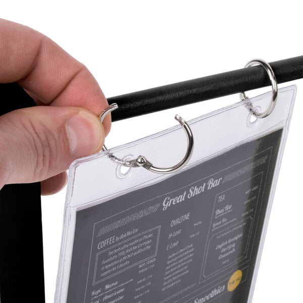 A hand holding a black wood Menu Solutions table tent with plastic sheet and rings.