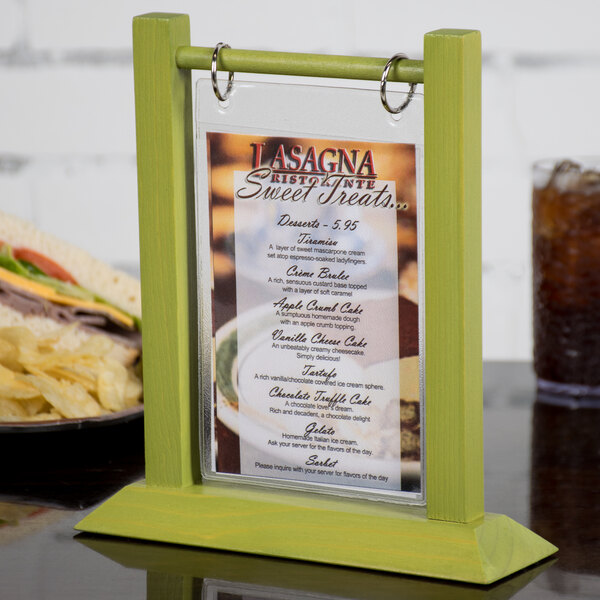 A Menu Solutions lime wood flip top table tent holding a menu on a table.