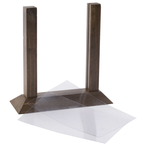 A Menu Solutions walnut wood table tent on a table with clear plastic on it.