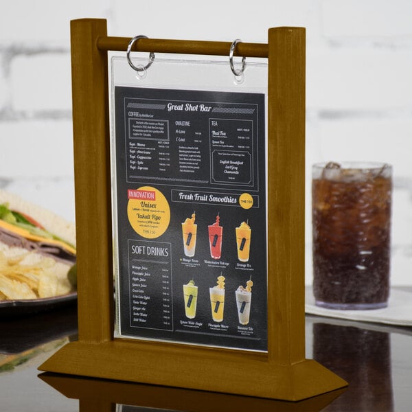 A Menu Solutions walnut wood table tent on a table with a drink.