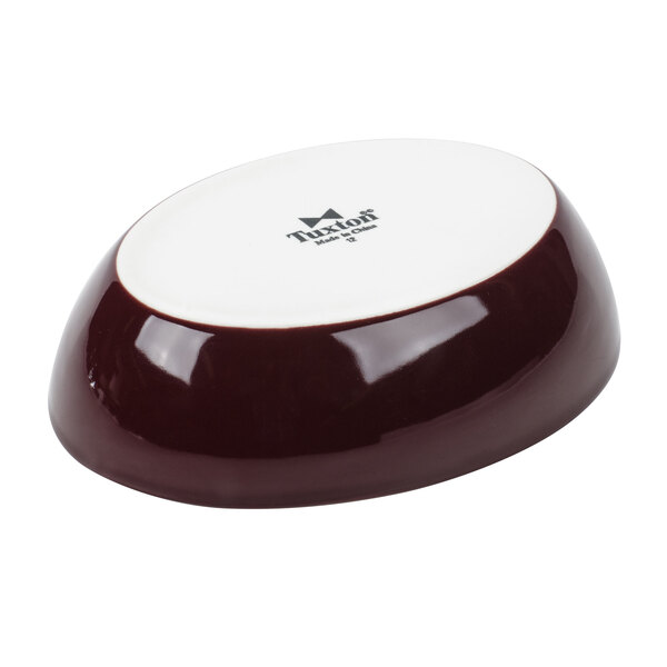 A Tuxton burgundy and eggshell oval bowl with a lid.