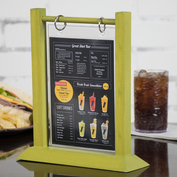 A Menu Solutions lime wood table tent on a table with a sandwich and a glass.