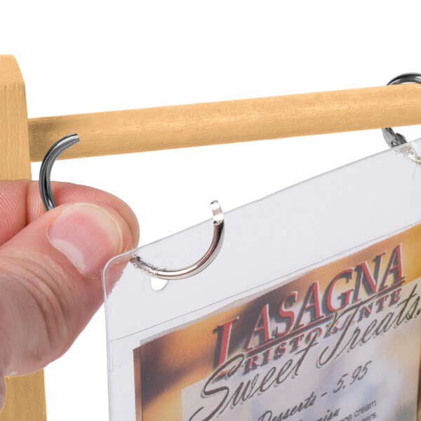 A hand holding a natural wood flip top table tent with paper inside.