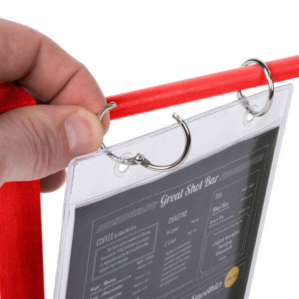 A hand holding a Menu Solutions Berry Wood Flip Top Table Tent with plastic sheet and rings.