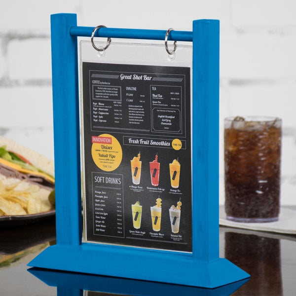 A Menu Solutions blue wood table tent with a drink on it.