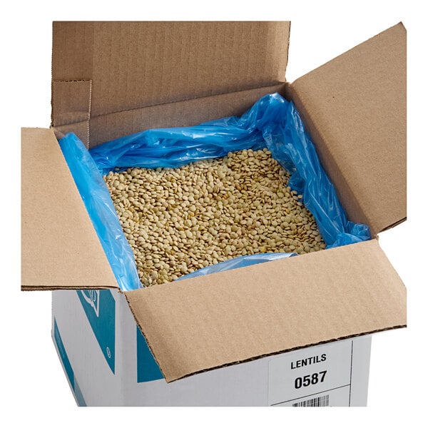A large cardboard box containing 20 pounds of dried lentil beans lined with a blue plastic bag.