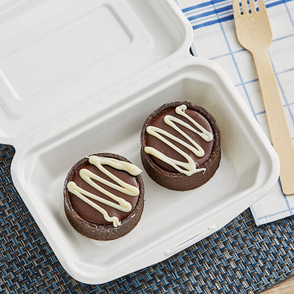 A chocolate cake with white frosting in a EcoChoice bagasse take-out container.