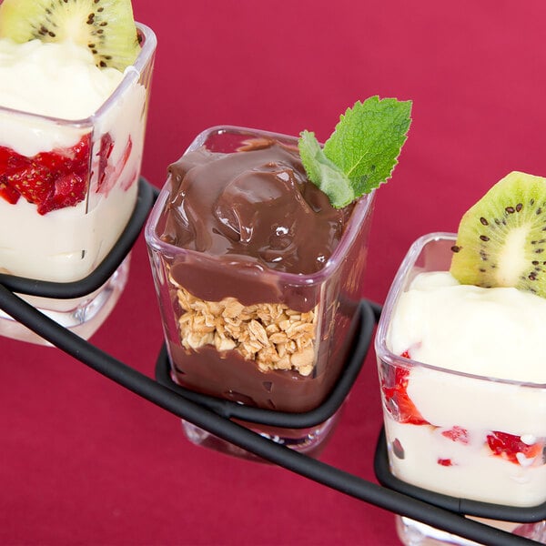 A group of desserts in GET SAN plastic square shot glasses. Each glass is filled with a dessert with fruit and chocolate.