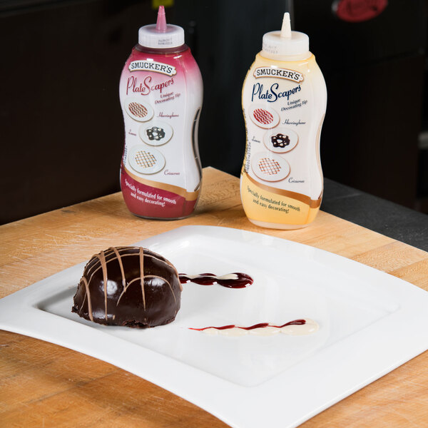 A chocolate dessert on a plate with a bottle of Smucker's Vanilla syrup on the table.