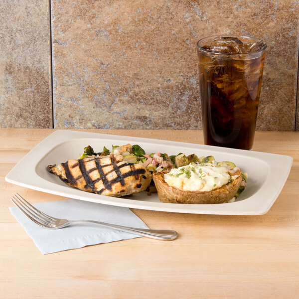 A matte sandstone oval platter with food on a table.