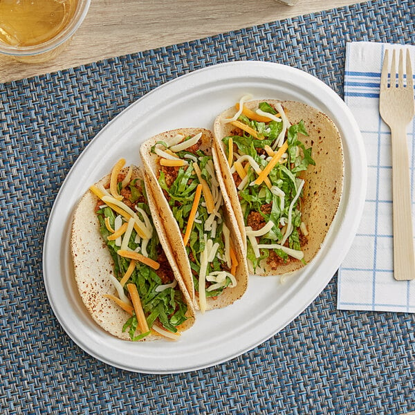 An EcoChoice Bagasse oval platter with two tacos on a table.