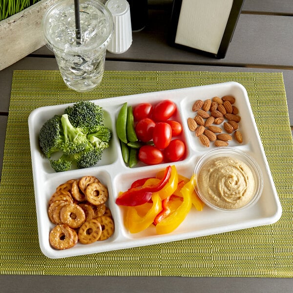 An EcoChoice compostable bagasse tray with compartments filled with a variety of food including vegetables and nuts.