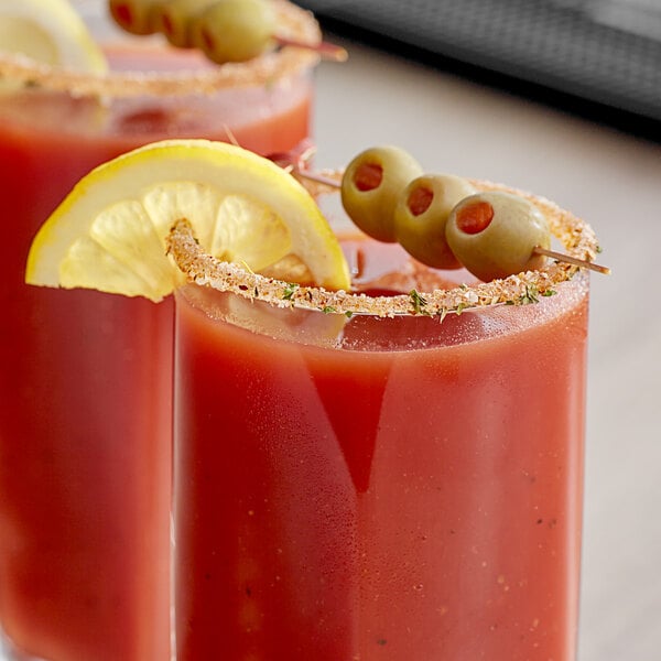 Two Bloody Mary drinks with Rokz Natural Bloody Mary Infused Cocktail Rimming Salt and lemon slices on a table in a brunch café.