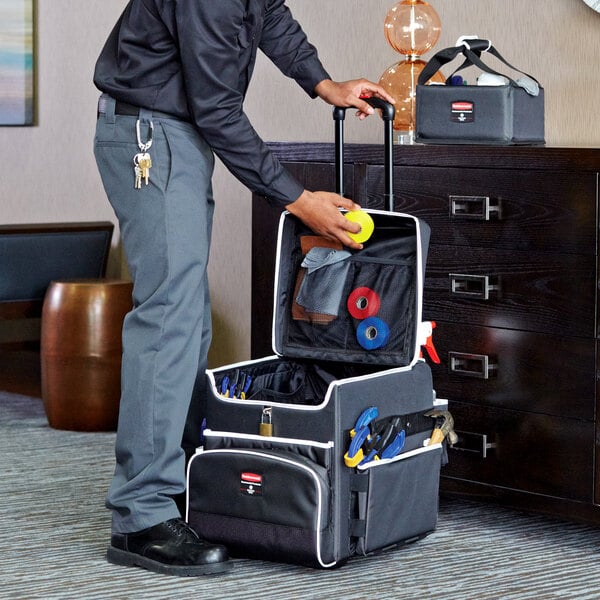 A man in a suit using a Rubbermaid Small Executive Quick Cart to store a tennis ball.