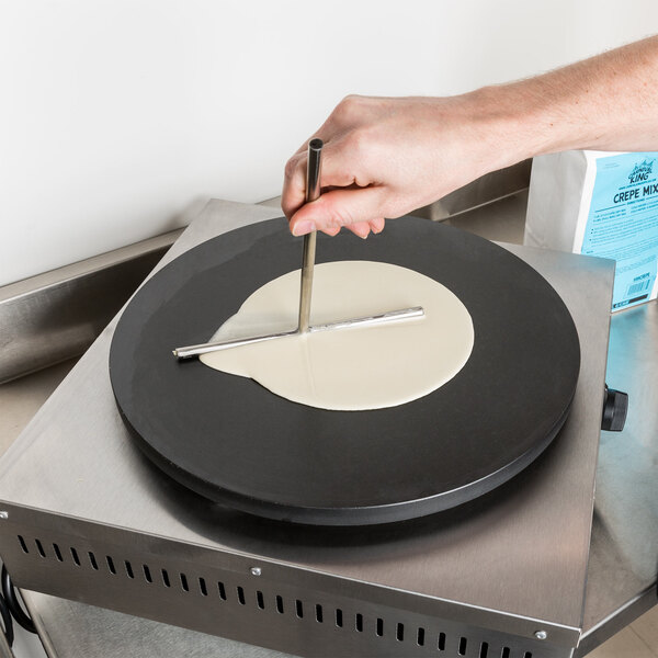 T-spreader being used to spread crepe batter over a crepe maker
