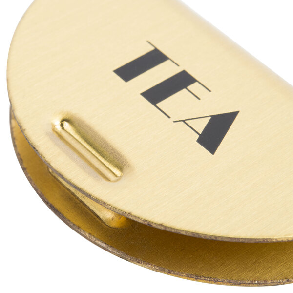 A gold metal "Tea" sign with brass finish for a Cambro beverage dispenser.