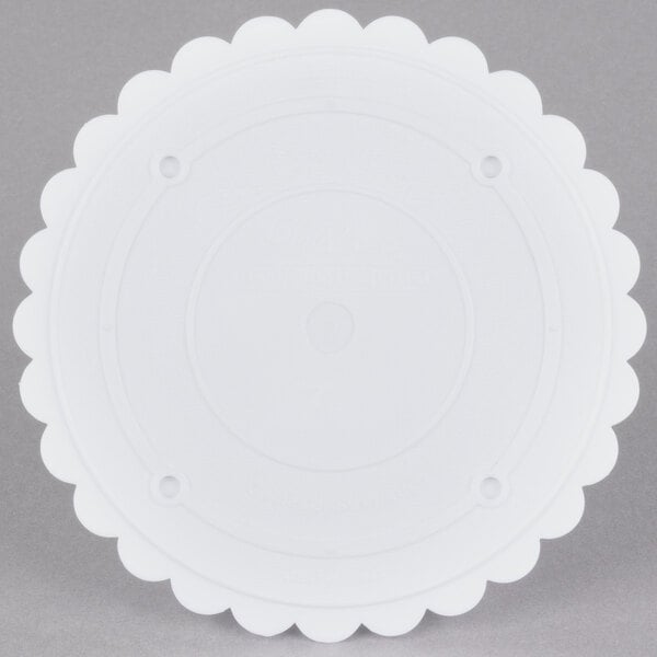 A white round Wilton cake separator plate with scalloped edges.