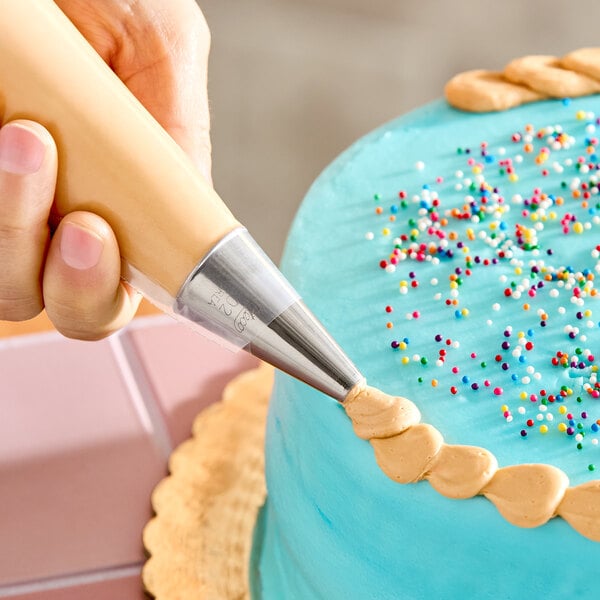 A metal Ateco 802 plain piping tip being used to decorate a cake with icing.