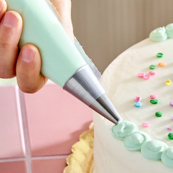 A plain piping tip being used to decorate a cake with icing.