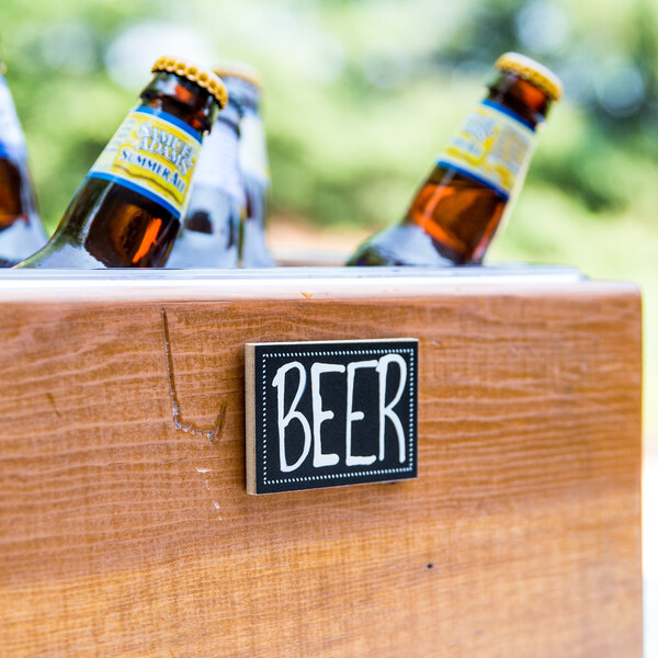 A Cal-Mil chalkboard label on a beer bottle in a wooden crate.
