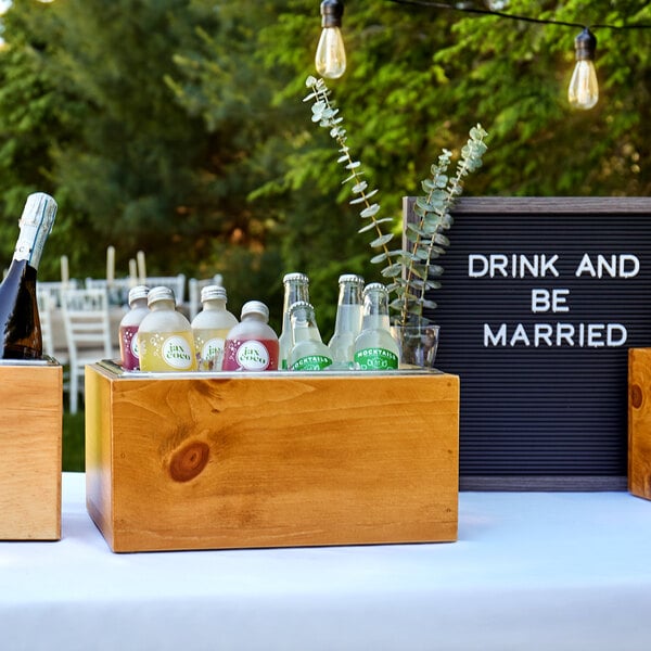 A Cal-Mil vintage wood ice housing on a table with bottles of champagne inside.