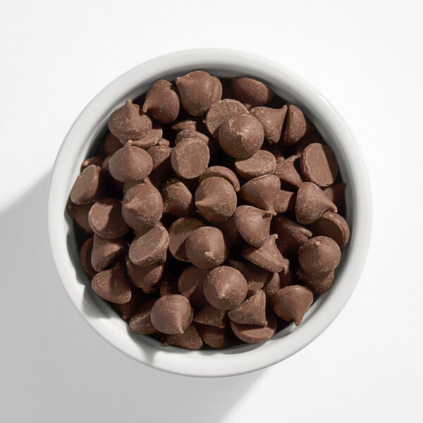 A white bowl filled with milk chocolate mini unwrapped baking kisses.