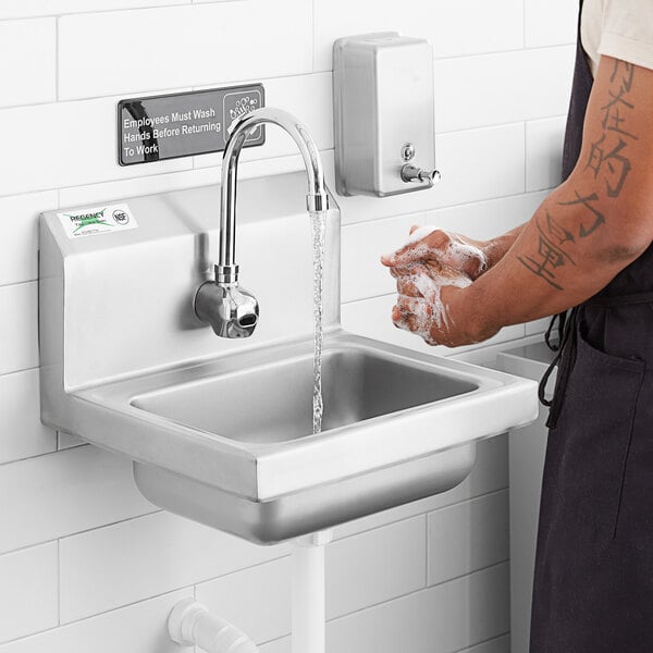 A person washing their hands in a Regency wall mounted hand sink.