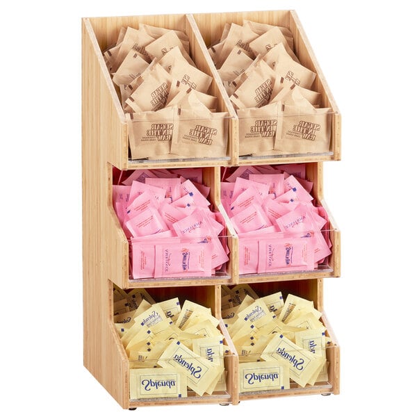 A wooden shelf with several clear bins holding coffee condiments.