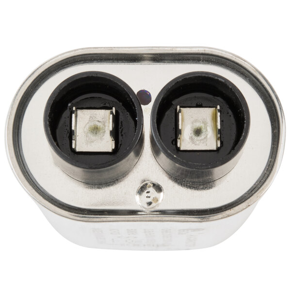 A close up of a Solwave capacitor with two metal electrical sockets.