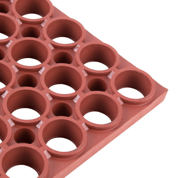 A close-up of a red rubber mat with holes in it.