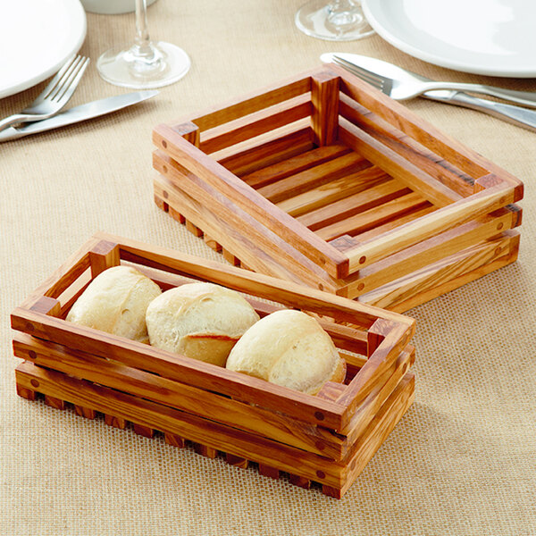 An American Metalcraft olive wood bread crate with bread inside on a table.