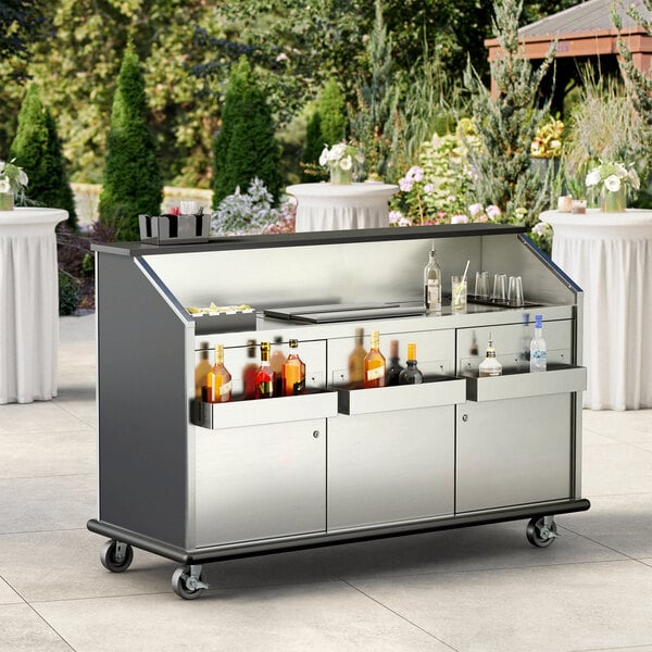 An Advance Tabco portable bar with bottles and glasses on wheels.