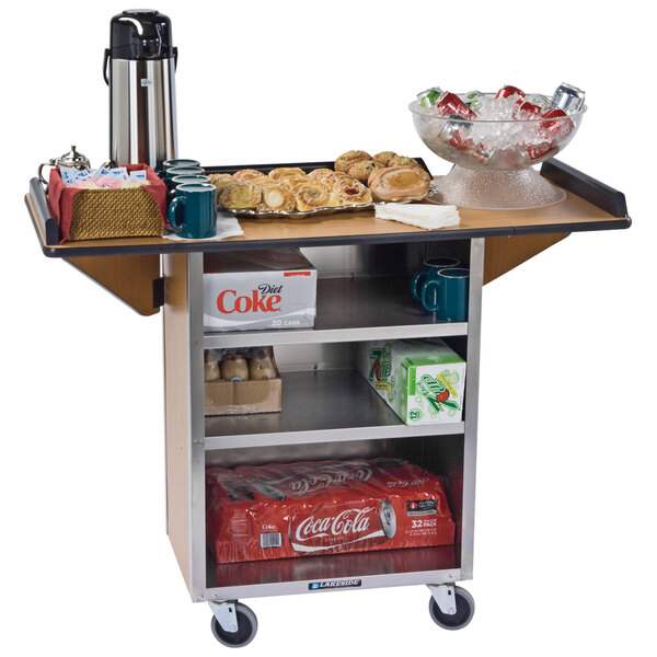 A Lakeside stainless steel drop-leaf beverage cart with soda and ice on it.