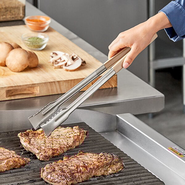 Vollrath tan Kool-Touch tongs picking up meat on a grill.