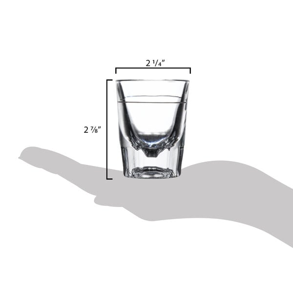 A hand holding a Libbey fluted shot glass with a 1 oz. pour line.