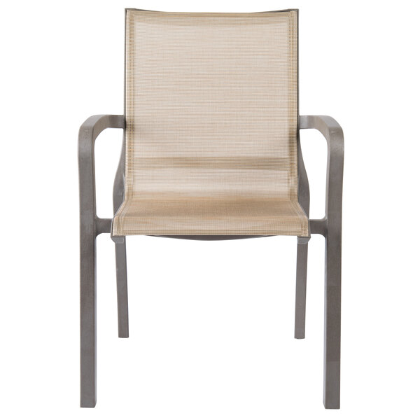A tan Grosfillex outdoor stacking armchair with metal legs.