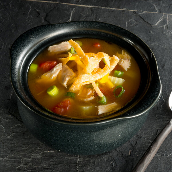 A black Hall China onion soup bowl filled with chicken and vegetables.