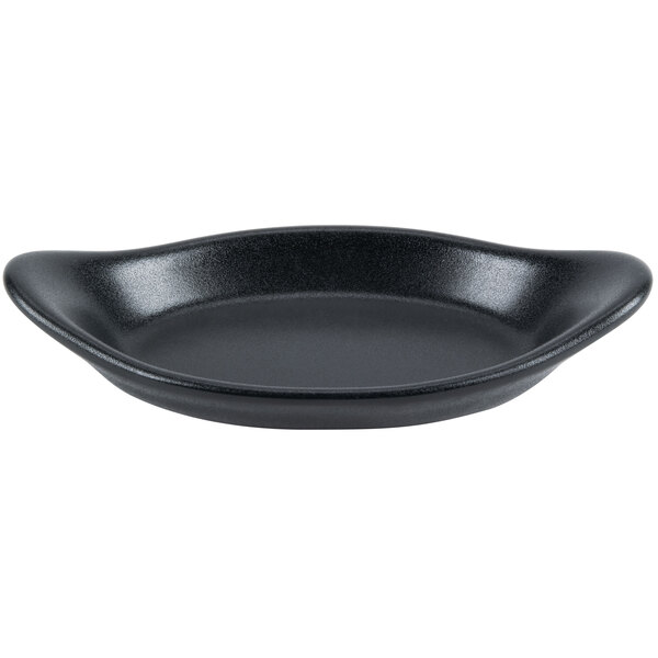 A black Hall China rarebit dish with a curved edge.