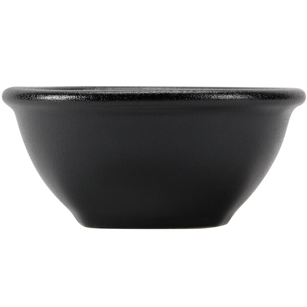 A close-up of a Hall China black sauce dish.