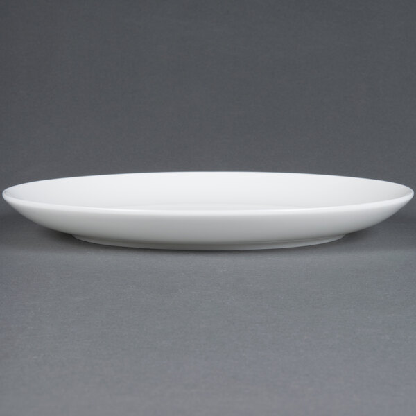 A CAC Majesty European bone china coupe plate with a rim on a gray surface.